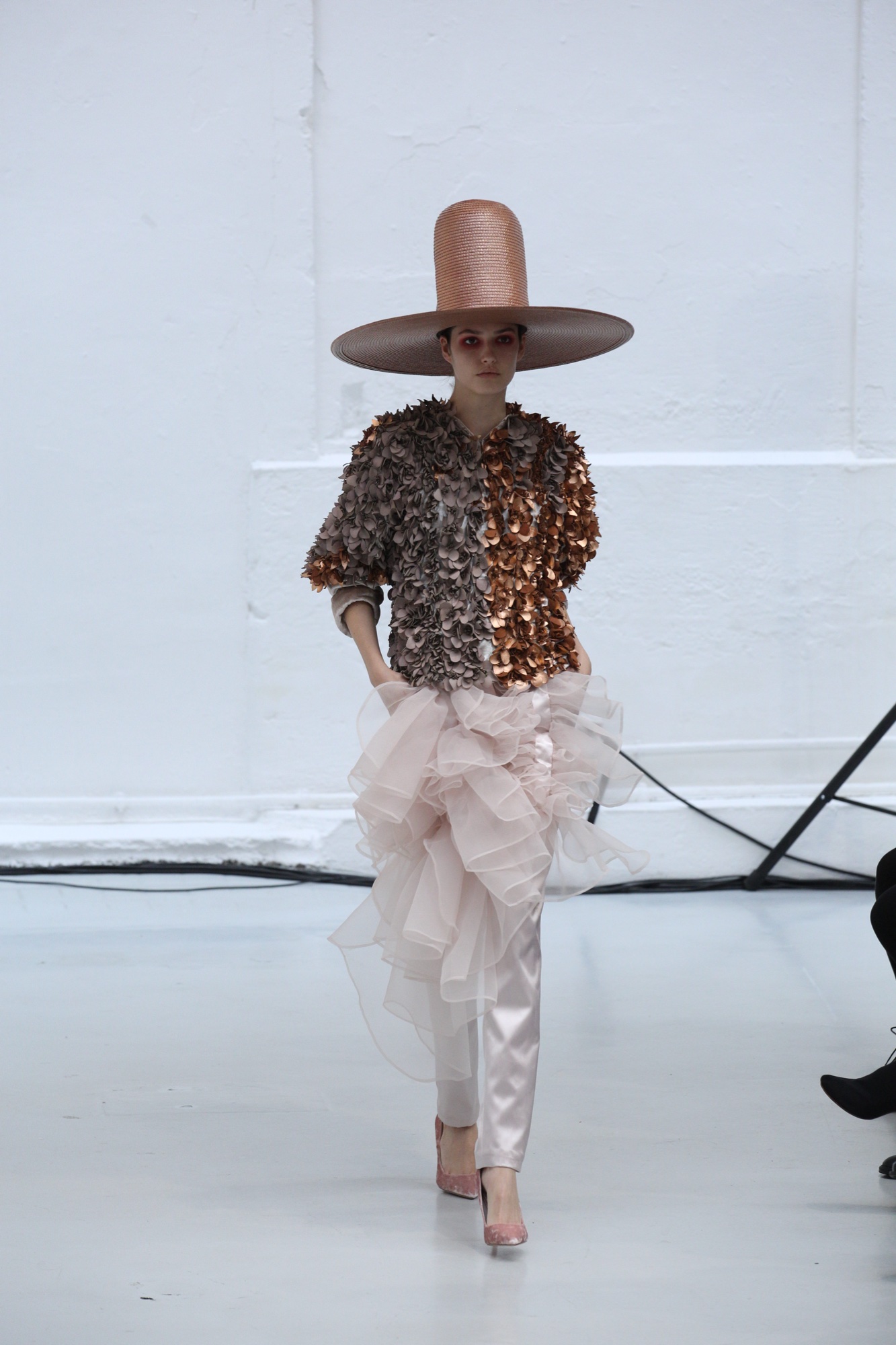 Model in a sculptural bronze hat and textured couture look
